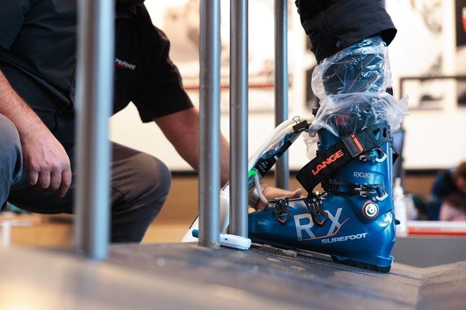A Surefoot fitter injecting a custom liner into a Lange ski boot