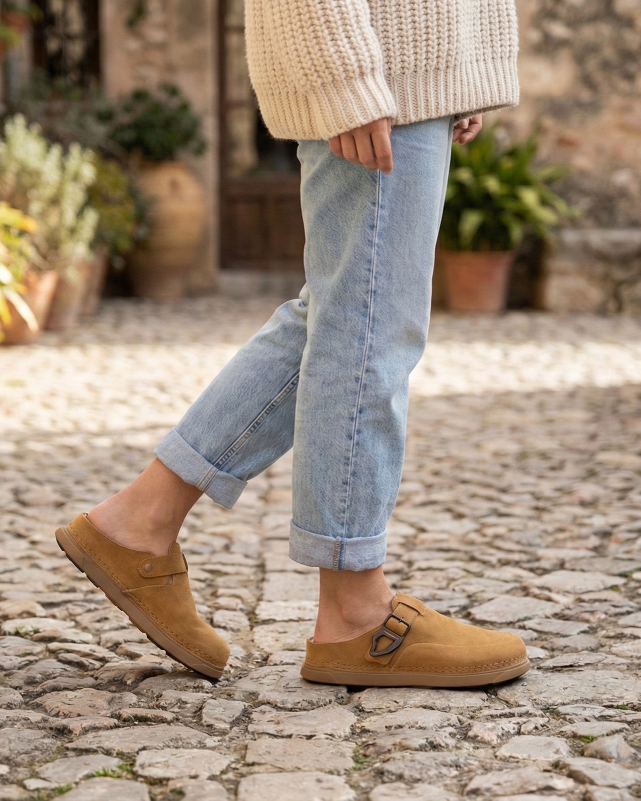 The Classic Clog in khaki suede, worn through a cobblestone village