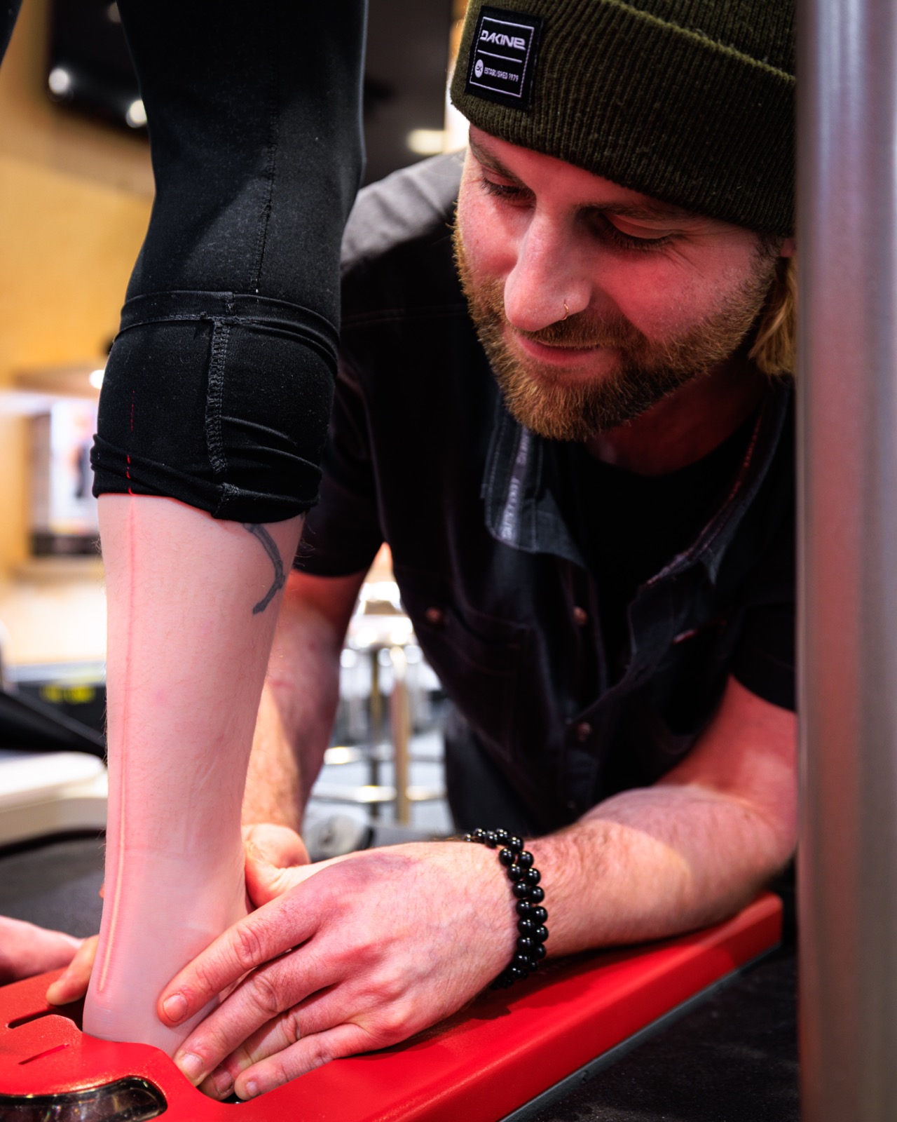 A Surefoot technician carefully checking a customer's foot and leg alignment during a boot fitting